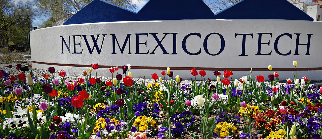 Image of the New Mexico Tech entry sign surrounded by blooming flowers