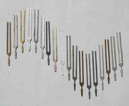 18 tuning forks lying on a table in a sine wave pattern