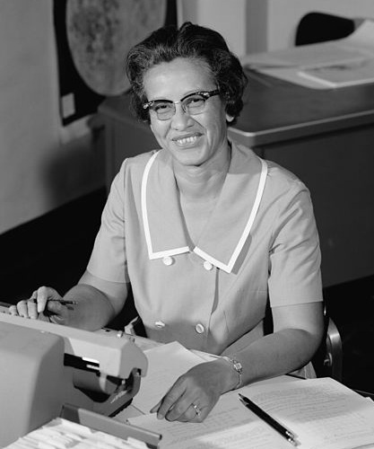 Katherine Johnson seated at a calculator.