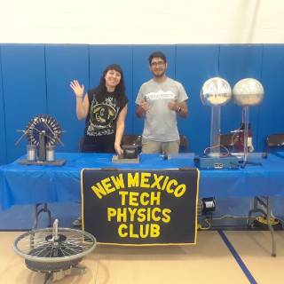 Physics Club NMT Physics Club table with two members waving