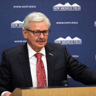 Image of President Wells speaking at a podium with the New Mexico Tech logo.