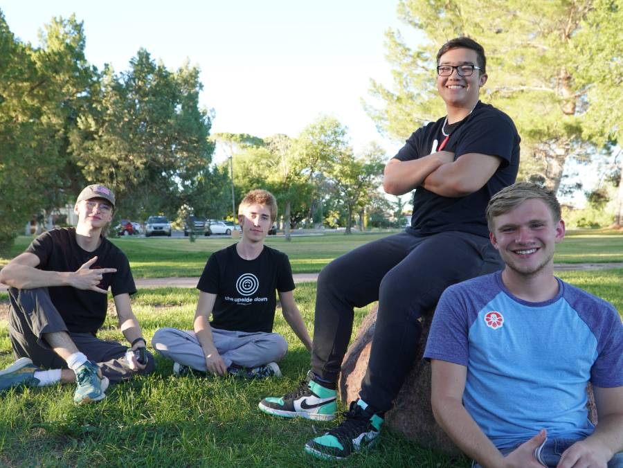 Four friends sit on the grass at the Welcome BBQ